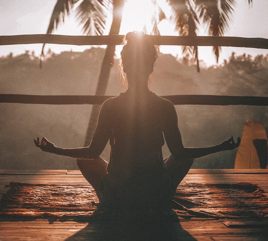 Calming reflection Silhouette of a person meditating at sunset, surrounded by palm trees.
